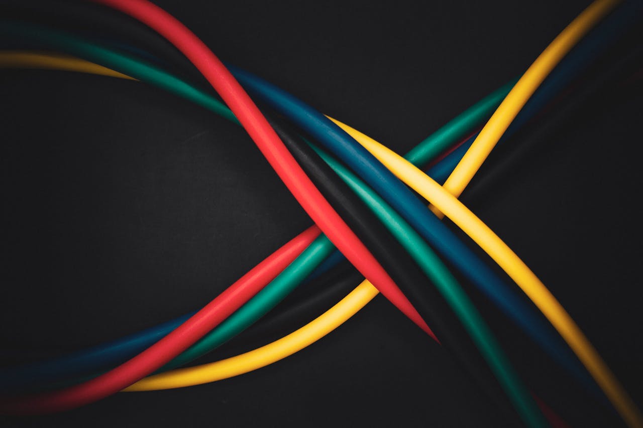 Multi-colored cables intertwined against a dark background, showing technology connections.