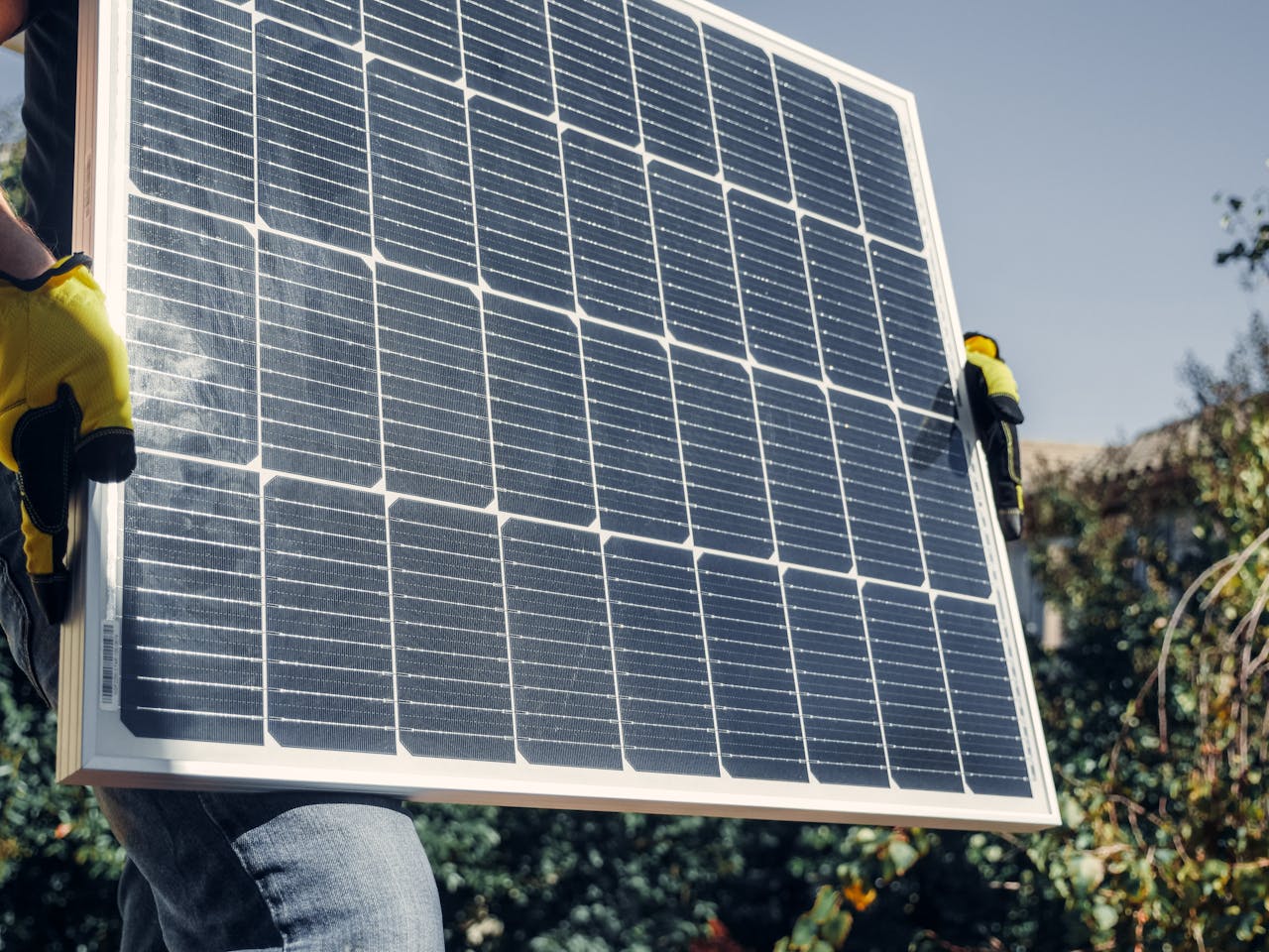 Close-up of technician with safety gear installing a solar panel outdoors.